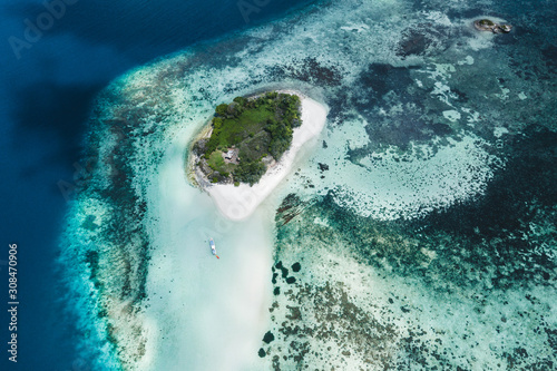 Small coral reef island with white sand beach. Aerial drone view from above. Tropical background.