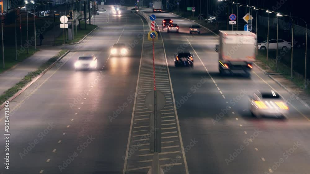 Aerial view of fast moving freeway traffic at night. Road goes beyond the horizon. Street lights illuminate the track. Parked cars on the side of the road. Background. Time Lapse 4K. Ultra HD footage Aerial view of fast moving freeway traffic at night. Road goes beyond the horizon. Street lights illuminate the track. Parked cars on the side of the road. Background. Time Lapse 4K. Ultra HD footage