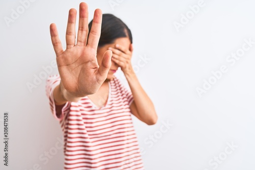 Beautiful redhead woman wearing casual striped red t-shirt over isolated background covering eyes with hands and doing stop gesture with sad and fear expression. Embarrassed and negative concept.