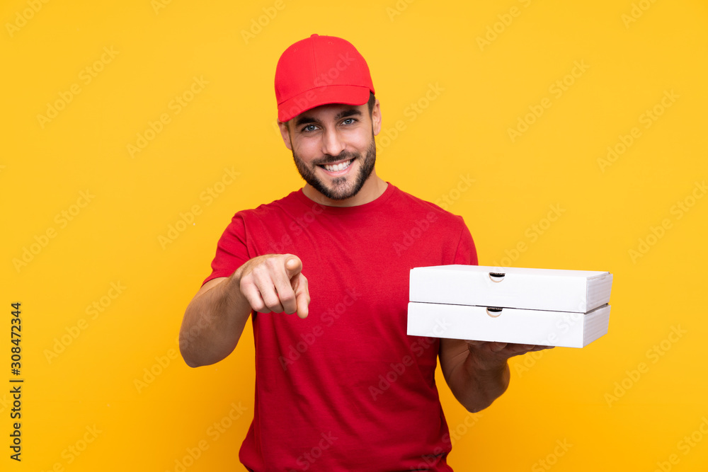 pizza delivery man with work uniform picking up pizza boxes over isolated yellow background points finger at you with a confident expression pizza delivery man with work uniform picking up pizza boxes over isolated yellow background points finger at you with a confident expression