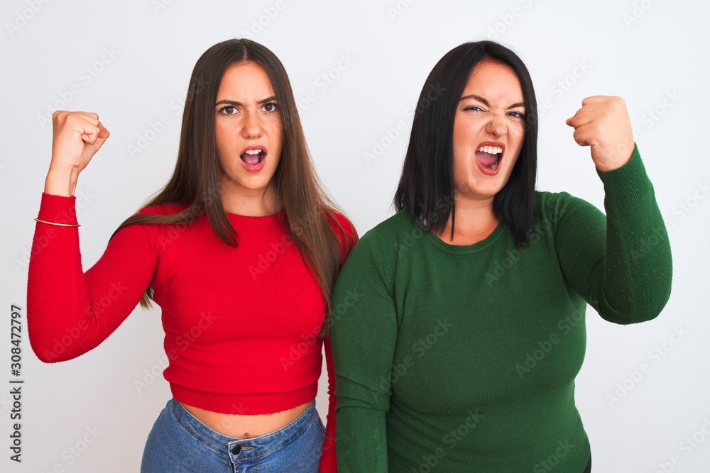 Young beautiful women wearing casual clothes standing over isolated white background angry and mad raising fist frustrated and furious while shouting with anger. Rage and aggressive concept. Young beautiful women wearing casual clothes standing over isolated white background angry and mad raising fist frustrated and furious while shouting with anger. Rage and aggressive concept.