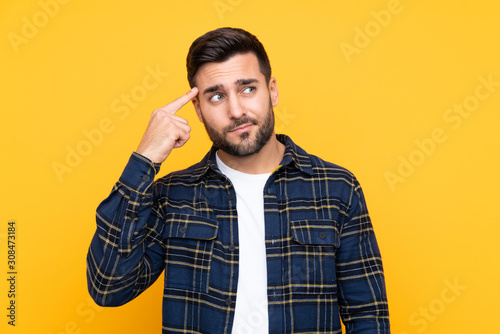 Bild auf Leinwand Young handsome man with beard over isolated yellow background making the gesture