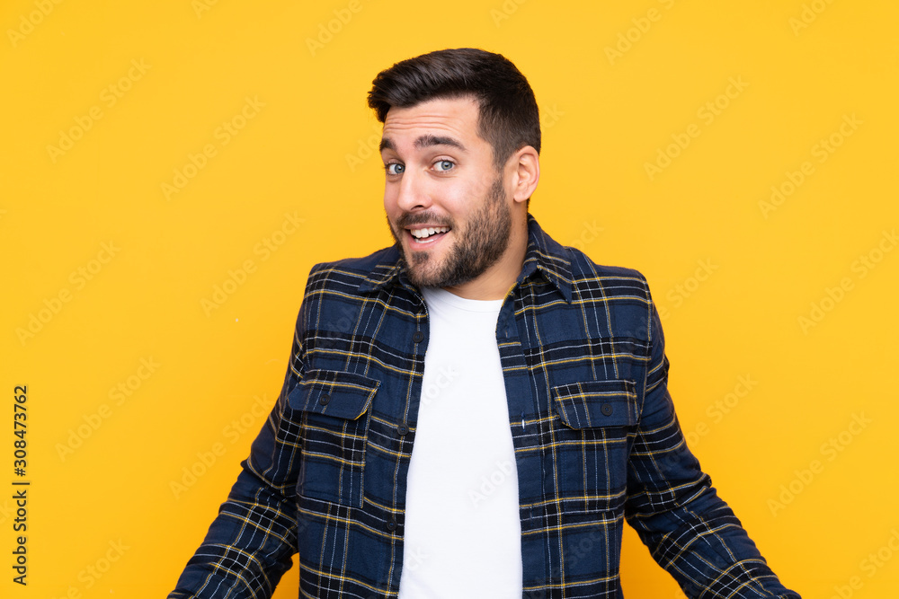 Young handsome man with beard over isolated yellow background smiling Young handsome man with beard over isolated yellow background smiling