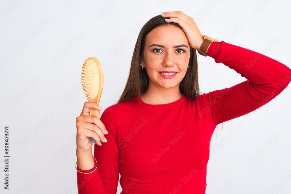 Young beautiful girl holding hair comb standing over isolated white background stressed with hand on head, shocked with shame and surprise face, angry and frustrated. Fear and upset for mistake. Young beautiful girl holding hair comb standing over isolated white background stressed with hand on head, shocked with shame and surprise face, angry and frustrated. Fear and upset for mistake.