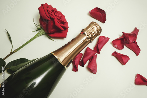 Fototapeta Naklejka Na Ścianę i Meble -  Beautiful red rose bud and petals with a bottle of champagne in white background. Valentines day concept with copy space