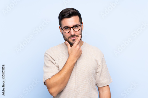 Young handsome man with beard over isolated blue background thinking an idea