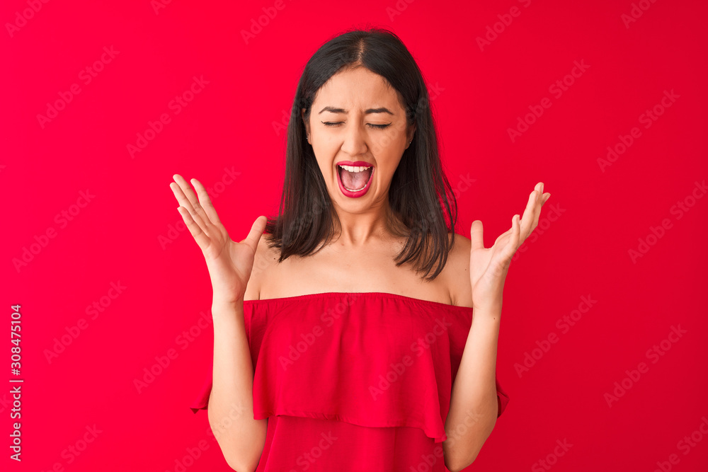 Young beautiful chinese woman wearing casual t-shirt standing over isolated red background celebrating mad and crazy for success with arms raised and closed eyes screaming excited. Winner concept Young beautiful chinese woman wearing casual t-shirt standing over isolated red background celebrating mad and crazy for success with arms raised and closed eyes screaming excited. Winner concept