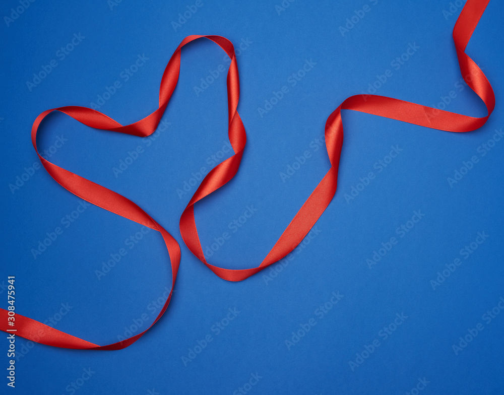 red silk thin ribbon twisted on a blue background red silk thin ribbon twisted on a blue background
