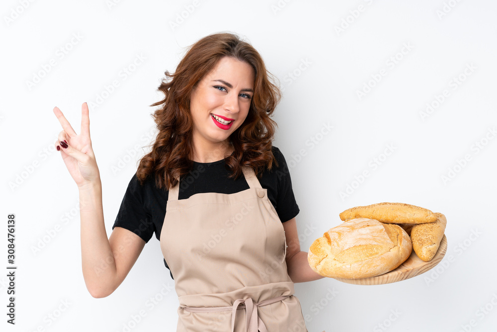 Woman in chef uniform. Female baker holding a table with several breads smiling and showing victory sign Woman in chef uniform. Female baker holding a table with several breads smiling and showing victory sign