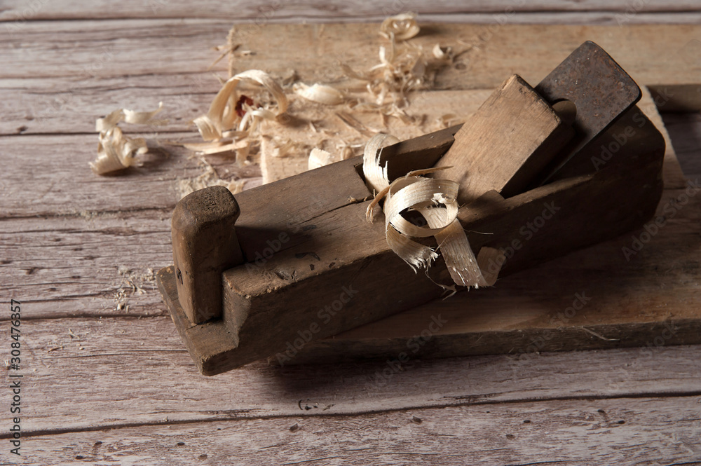 Working tool of a carpenter. Old wooden jointer, boards and shavings close-up on wooden background.
