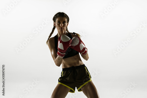 Fit caucasian woman in sportswear boxing isolated on white studio background. Novice female caucasian boxer training and practicing in motion and action. Sport, healthy lifestyle, movement concept.