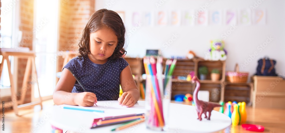 Beautiful toddler girl drawing cute draw using colored pencils at kindergarten - obrazy, fototapety, plakaty 