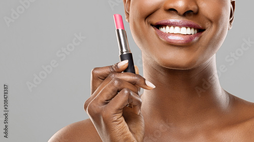 Beautiful afro girl holding pink lipstick in hand and smiling