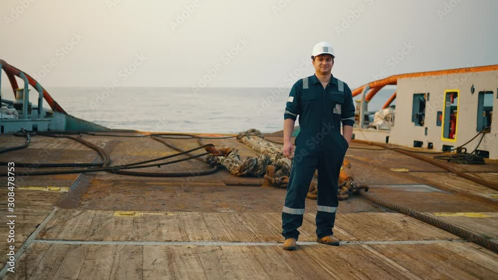 Marine Deck Officer or Chief mate on deck of offshore vessel or ship , wearing PPE personal protective equipment - helmet, coverall. He is looking at the camera Marine Deck Officer or Chief mate on deck of offshore vessel or ship , wearing PPE personal protective equipment - helmet, coverall. He is looking at the camera