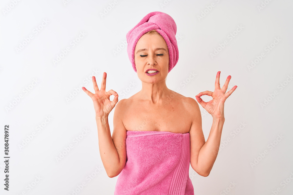 Middle age woman wearing shower towel after bath standing over isolated white background relax and smiling with eyes closed doing meditation gesture with fingers. Yoga concept. Middle age woman wearing shower towel after bath standing over isolated white background relax and smiling with eyes closed doing meditation gesture with fingers. Yoga concept.