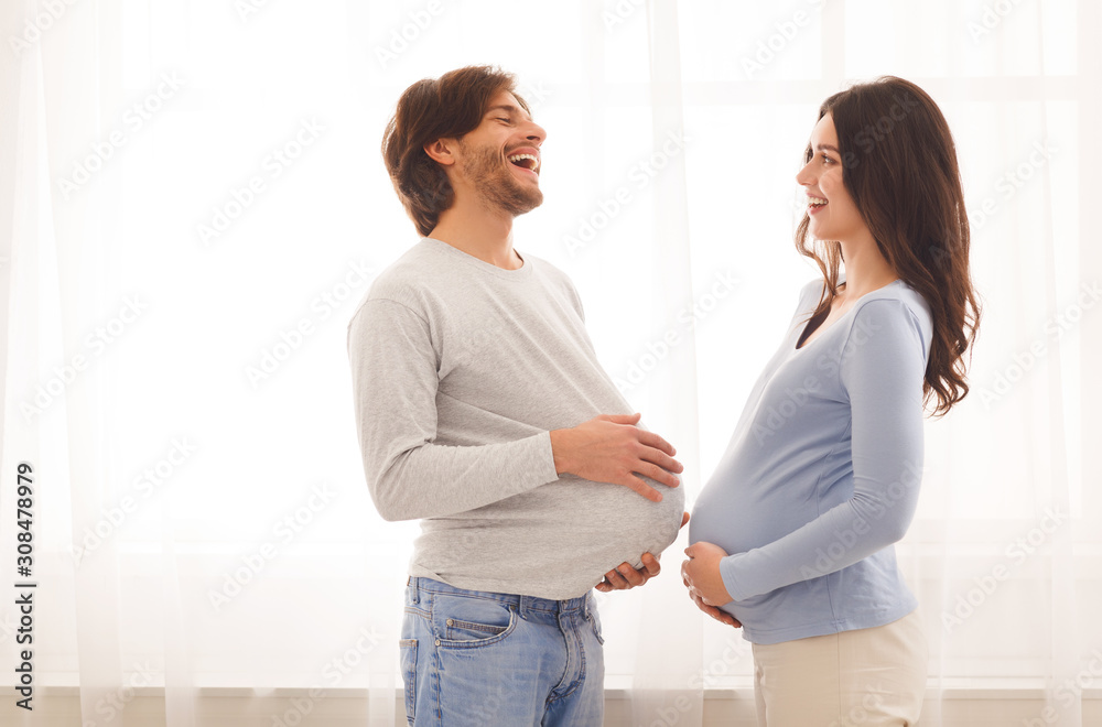 Funny portrait of pregnant woman and her husband with fake belly