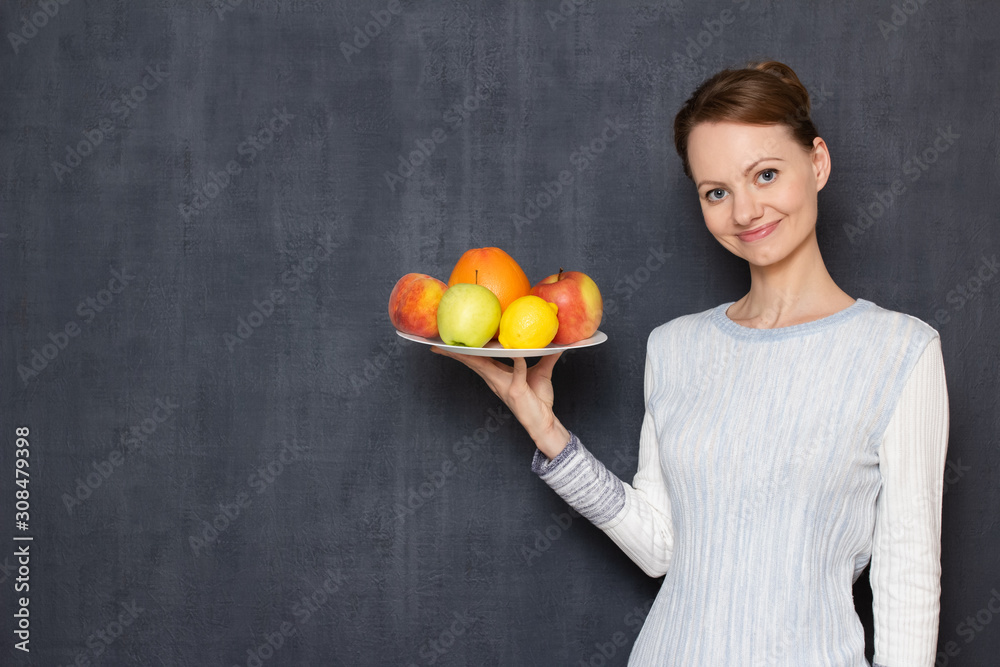 Portrait of happy girl holding white plate with ripe appetising fruits Portrait of happy girl holding white plate with ripe appetising fruits