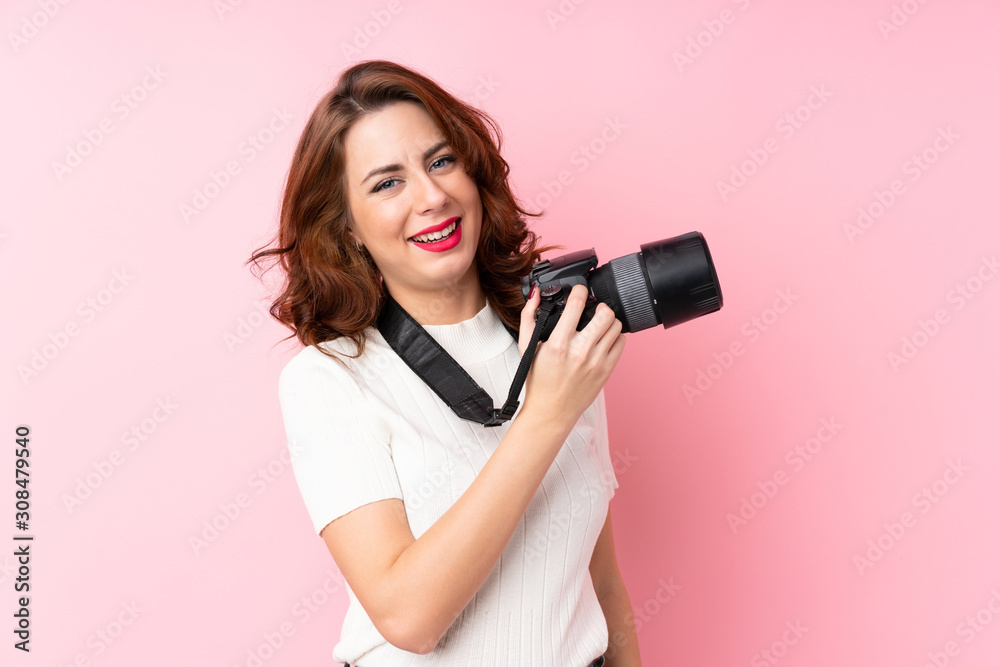Young Russian woman over isolated pink background with a professional camera