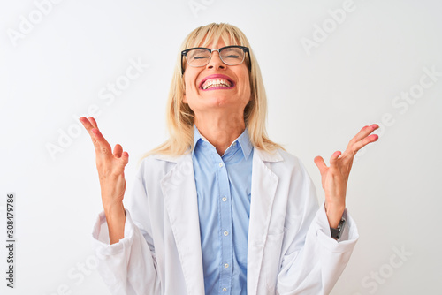 Middle age scientist woman wearing glasses standing over isolated white background celebrating mad and crazy for success with arms raised and closed eyes screaming excited. Winner concept