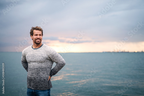Mature man standing outdoors on beach at dusk. Copy space.