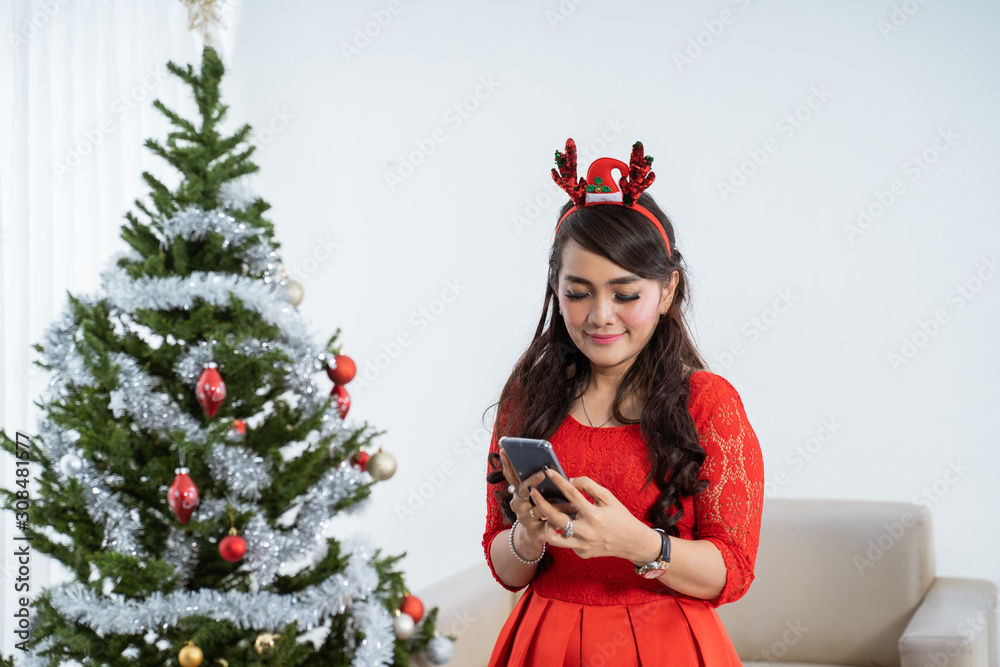attractive asian woman in red dress using mobile phone on chritstmas day attractive asian woman in red dress using mobile phone on chritstmas day