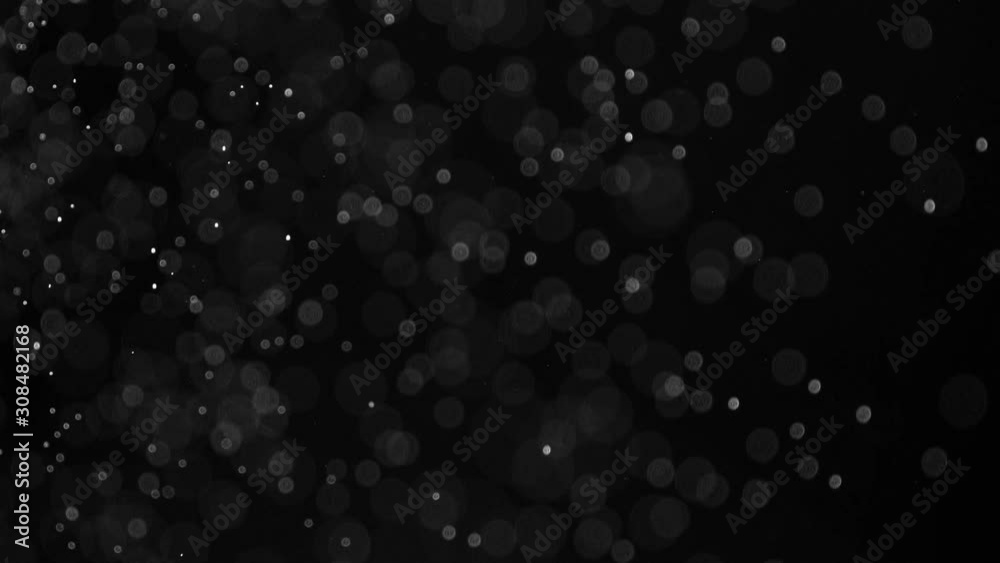 Falling Slowly Blurred Particles. Small white particles flow in the air on a black background to simulate snow, blizzard, or a microcosm of the Christmas magic. Filmed at a speed of 120fps Falling Slowly Blurred Particles. Small white particles flow in the air on a black background to simulate snow, blizzard, or a microcosm of the Christmas magic. Filmed at a speed of 120fps
