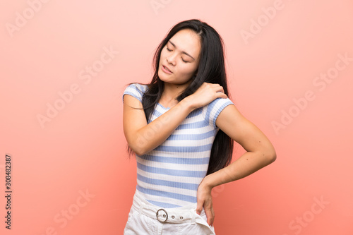Teenager asian girl over isolated pink background suffering from pain in shoulder for having made an effort