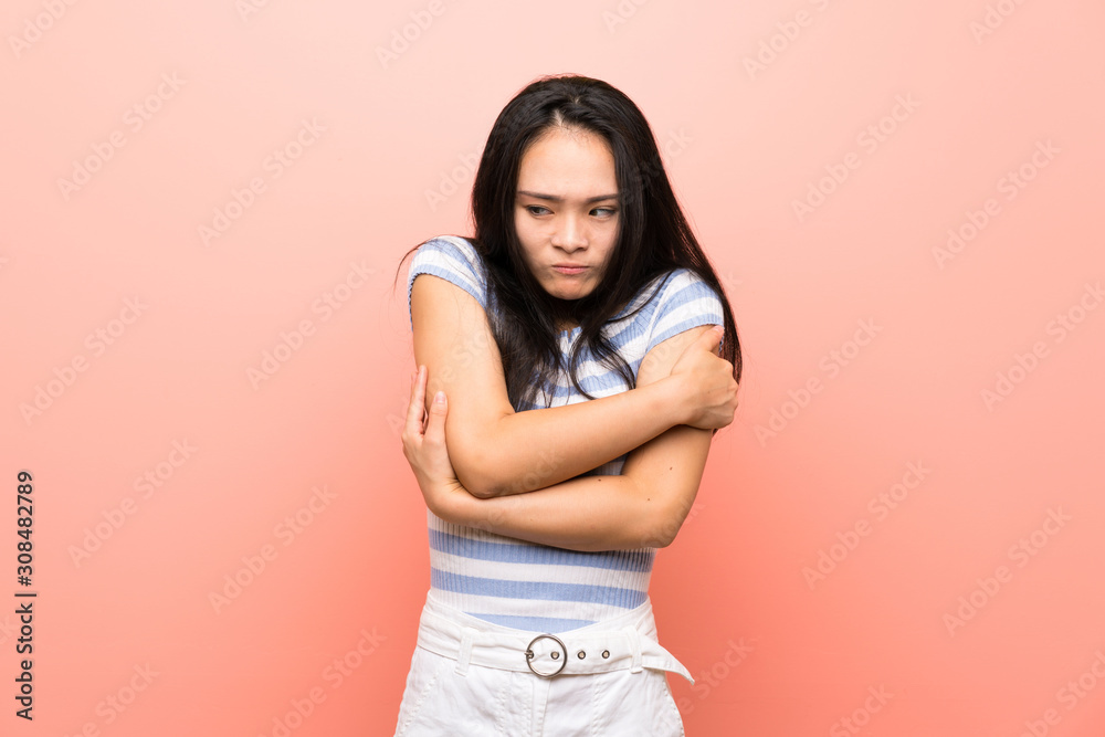 Teenager asian girl over isolated pink background freezing Teenager asian girl over isolated pink background freezing