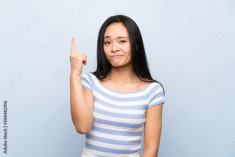Teenager asian girl over isolated blue background pointing with the index finger a great idea Teenager asian girl over isolated blue background pointing with the index finger a great idea