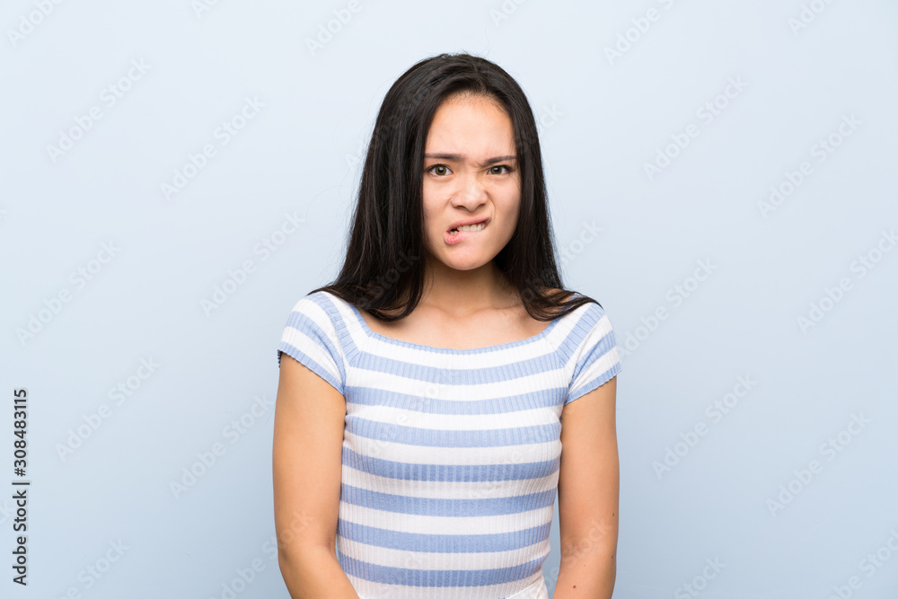 Teenager asian girl over isolated blue background having doubts and with confuse face expression Teenager asian girl over isolated blue background having doubts and with confuse face expression