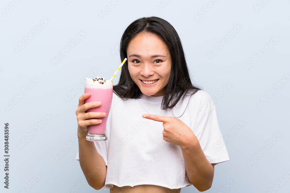 Teenager asian girl holding a strawberry milkshake with surprise facial expression Teenager asian girl holding a strawberry milkshake with surprise facial expression