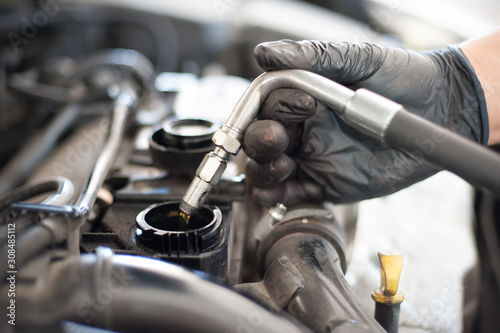 Auto mechanic repairer pours new motor oil into car engine