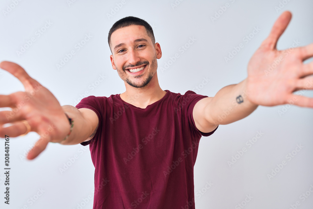 Young handsome man standing over isolated background looking at the camera smiling with open arms for hug. Cheerful expression embracing happiness. Young handsome man standing over isolated background looking at the camera smiling with open arms for hug. Cheerful expression embracing happiness.