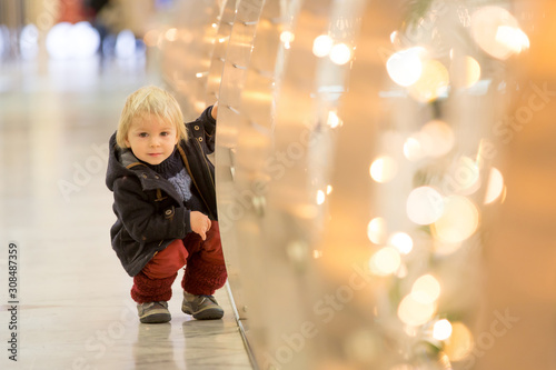 Fashion toddler boy in the city center shopping mall on Christmas
