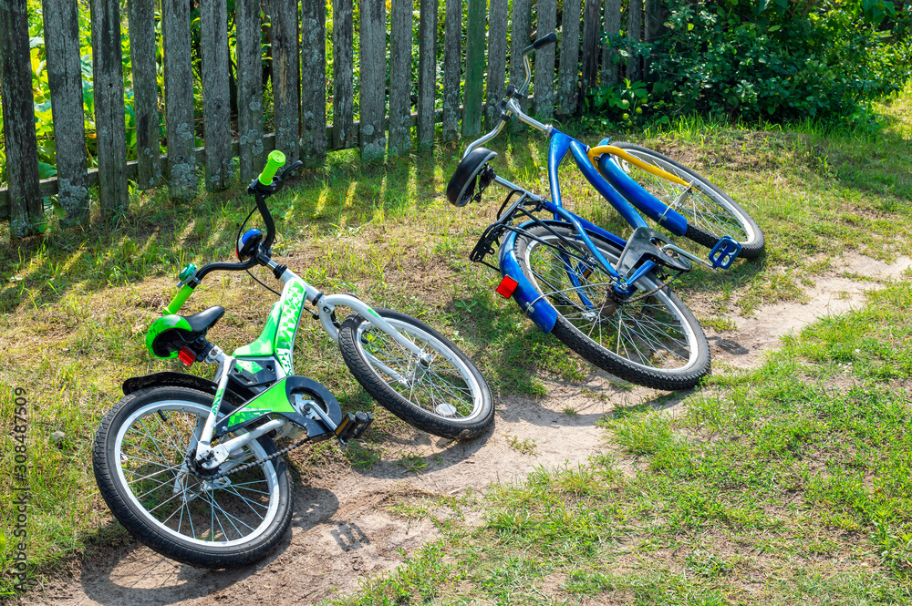 Two bicycles, one for children and one for adults, lie on the side of the countryside in summer or on vacation
