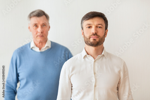Middle-Aged Son And Elderly Father Standing On White Background