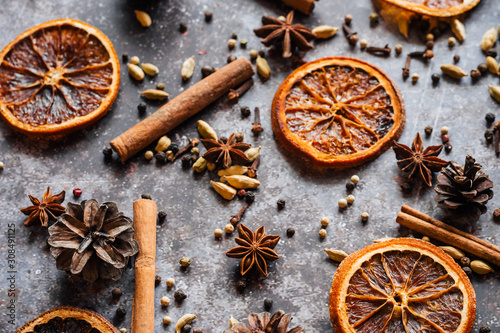 Christmas spice background. Cinnamon, cloves, pepper, dried oranges and anise on a grey background.