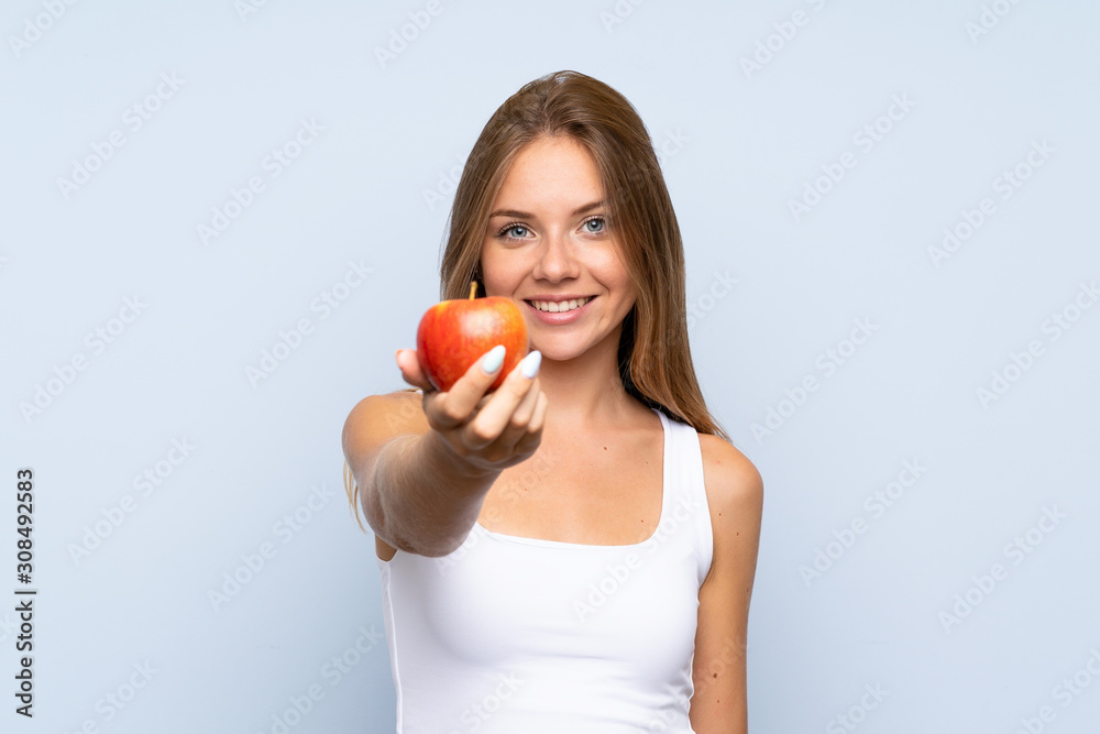 Young blonde girl with an apple over isolated background Young blonde girl with an apple over isolated background