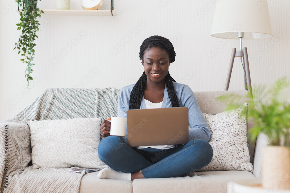 Young afro girl working with laptop on couch at home Young afro girl working with laptop on couch at home