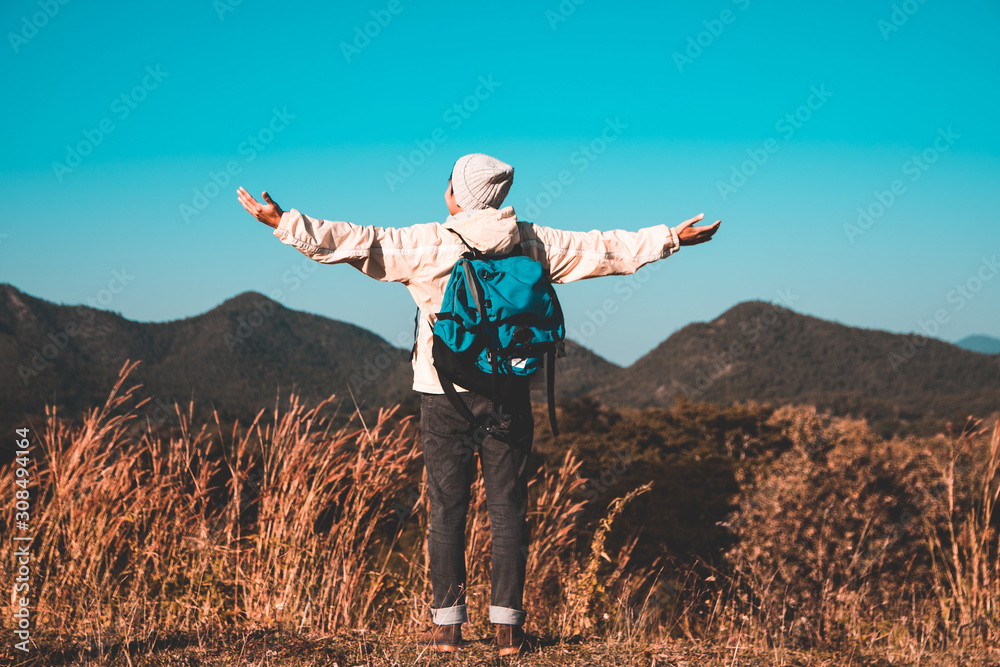 Blurred soft focus, Asian young man in long shirt and gray hat Carrying backpack hiking standing open arm happy at mountain peak above clouds and blue sky Hiker outdoor. Lamphun Province in morning Blurred soft focus, Asian young man in long shirt and gray hat Carrying backpack hiking standing open arm happy at mountain peak above clouds and blue sky Hiker outdoor. Lamphun Province in morning