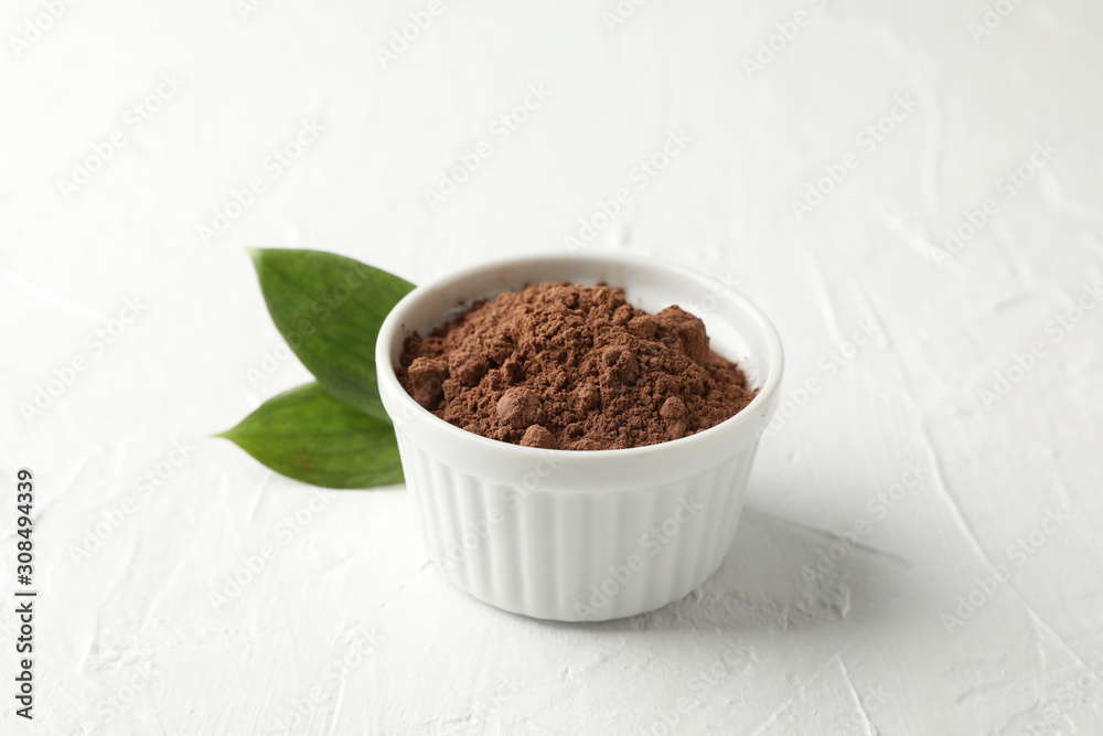 Bowl with cocoa powder and leaves on white background, closeup Bowl with cocoa powder and leaves on white background, closeup