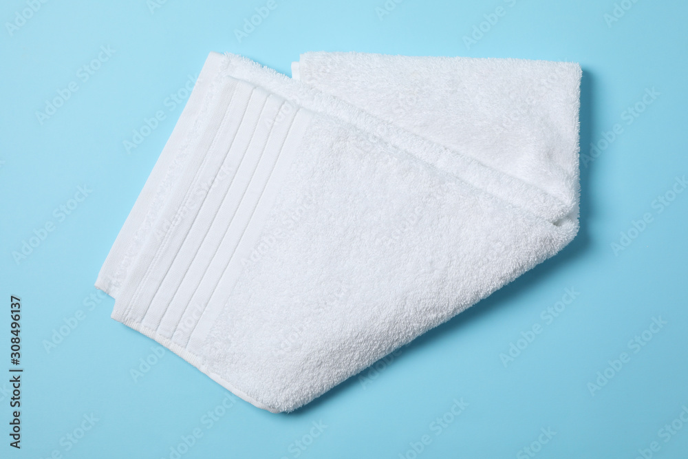 Fresh white towel on blue background, close up and top view