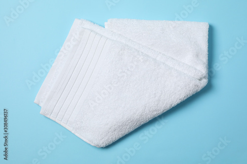 Fresh white towel on blue background, close up and top view
