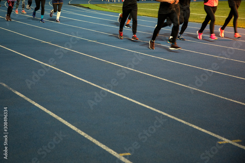 Runners at the stadium. Athletes are involved in athletics. Treadmills with markings. Legs of running people. A group of athletes in the stadium.