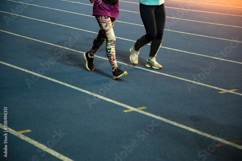 Runners at the stadium. Athletes are involved in athletics. Treadmills with markings. Legs of running people. Two athletes are running on the stadium. © Kozachenko Oleksandr