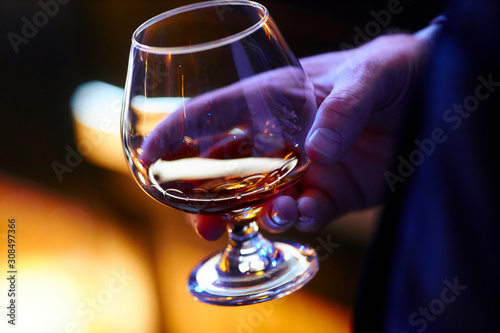 man aristocratically holds a glass of whiskey photo
