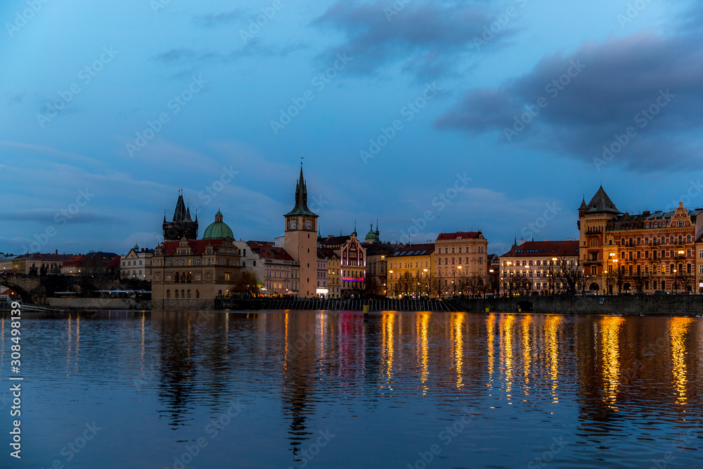 The center of Prague Czech Republic and its biggest landmark on the Vltava river Charles Bridge and the beautiful waterfront illuminated during Christmas at sunset with reflections