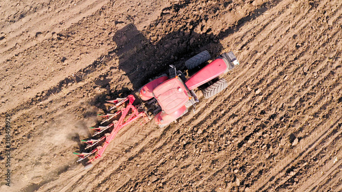 Red Tractor Cultivating a large field, Aerial image. © STOCKSTUDIO