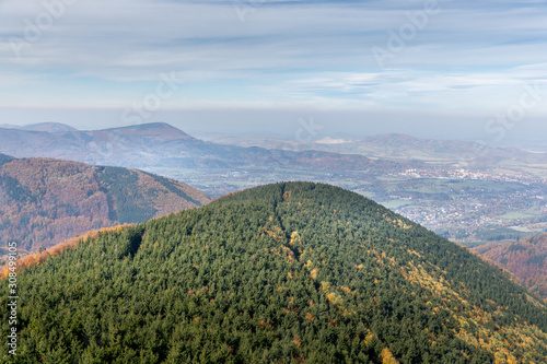 Hills and mountains on the horizon of beautiful nature with city in the forest valley view into vast distance of the Beskids Area during a windy sunny day captured in Radhost Pustevny area