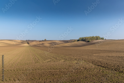 View of plowed land after the season in the Moravian Tuscany region s landscape full of ripples overlooking the village in the background during an afternoon sunny day without clouds